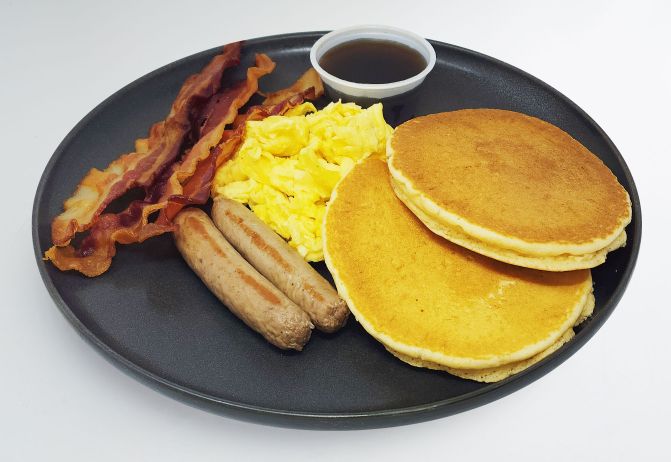 spartan meal preps miami - protein grand slam dish - 2 pancakes next to scrambled eggs, 2 sausage links, 2 bacon links and a house syrup cup. Healthy meal from spartan meal preps miami.