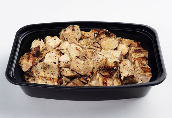 A black plastic container filled with chopped grilled chicken.