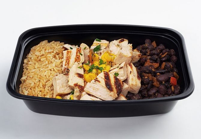 A plate containing grilled chicken breast pieces, brown rice, black beans, and roasted corn. - MEAL PREP BY SPARTAN MEAL PREPS MIAMI