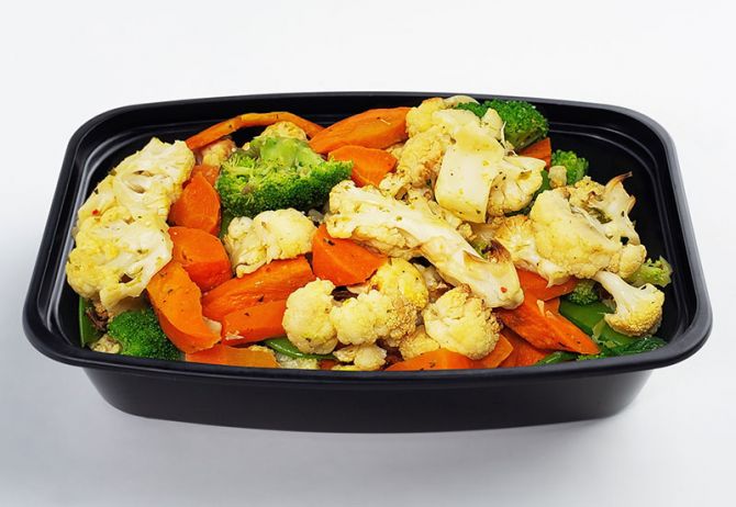 A black container filled with grilled vegetables, including broccoli, cauliflower, carrots, and sliced meat.