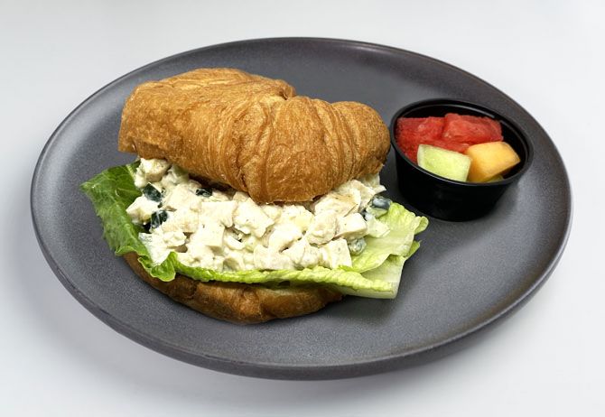 spartan meal preps miami - nanas chicken sandwich paired with fruit cup on a gray plate - healthy meal from spartan meal preps miami.