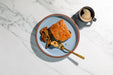 Plate with a piece of chocolate chip cookie and a cup of coffee on a marble surface