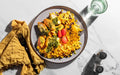 Plate of colorful rice dish with vegetables on a marble surface