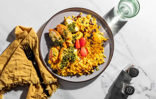 Plate of colorful rice dish with vegetables on a marble surface