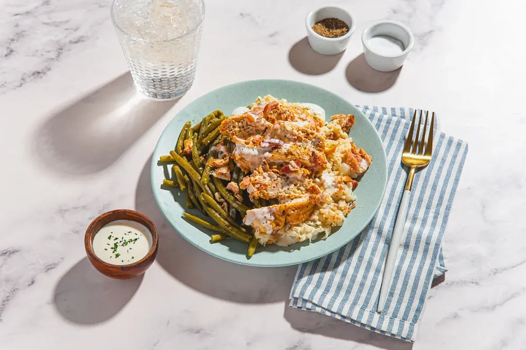 Plate of food with green beans and a side of sauce on a marble surface