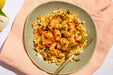 Plate of shrimp and rice dish on a pink cloth with a fork
