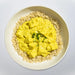 Yellow curry over brown rice on a white plate with a light gray background