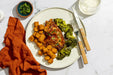 Plated meal with chicken, broccoli, and tater tots on a white plate with cutlery.