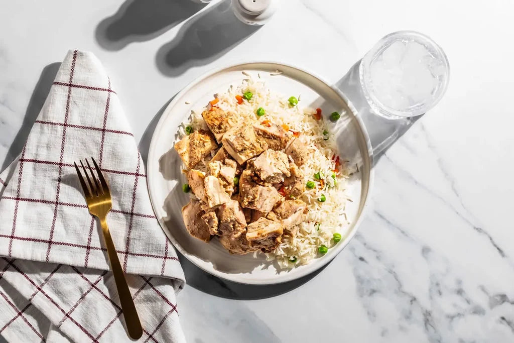 Bowl of rice with tofu and vegetables on a marble surface with a fork and towel.