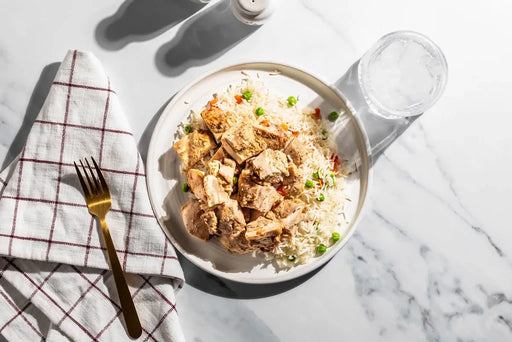 Bowl of rice with tofu and vegetables on a marble surface with a fork and towel.