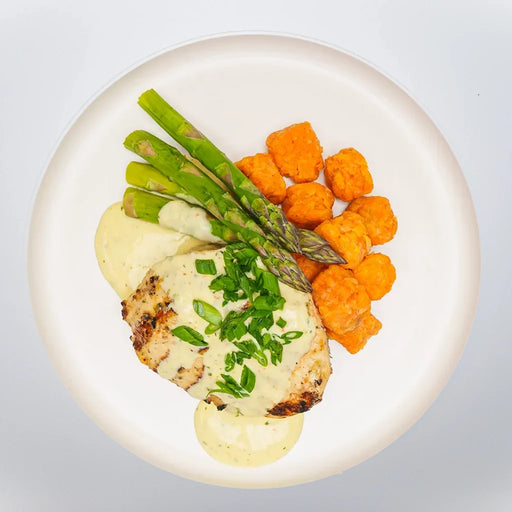 Plated dish with chicken, asparagus, and sweet potato gnocchi on a white plate.