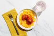 Plate of pasta with meatballs on a marble surface with a yellow napkin and fork.