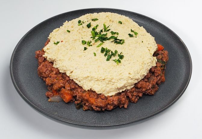 Layered dish with mashed topping and ground meat on a gray plate