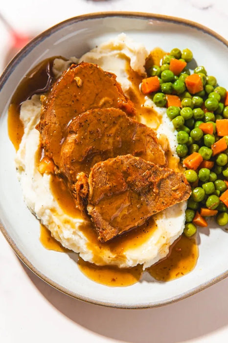 Plated dish with meat, mashed potatoes, and peas on a white plate.