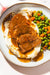 Plated dish with meat, mashed potatoes, and peas on a white plate.
