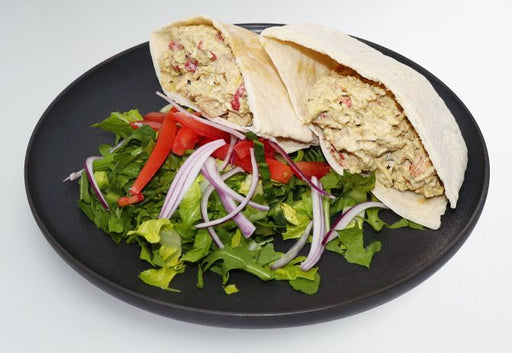Pita bread stuffed with a salad on a black plate. A meal made by spartan meal preps miami.
