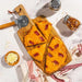 Wooden cutting board with pizza slices, cheese, and pepper shakers on a marble surface.