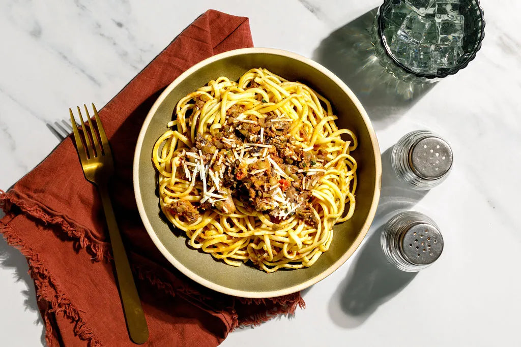  bowl of spaghetti with a red napkin and fork on a marble surface