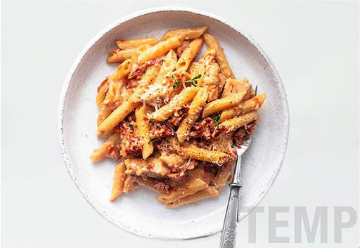 Plate of penne pasta with sauce on a white background